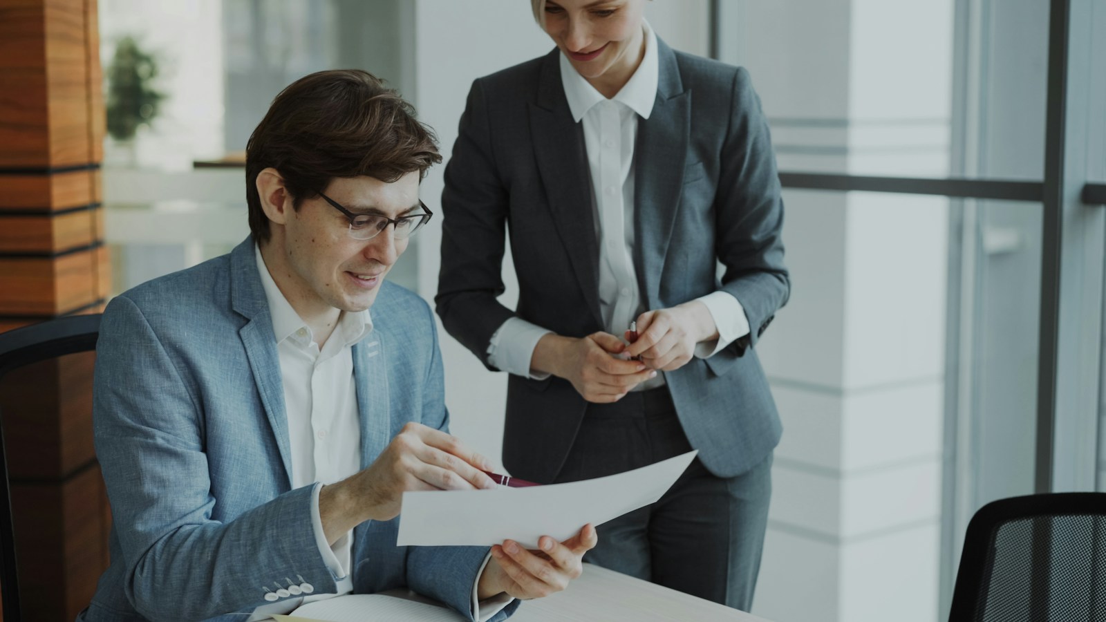 Two colleagues smiling as they review a document together