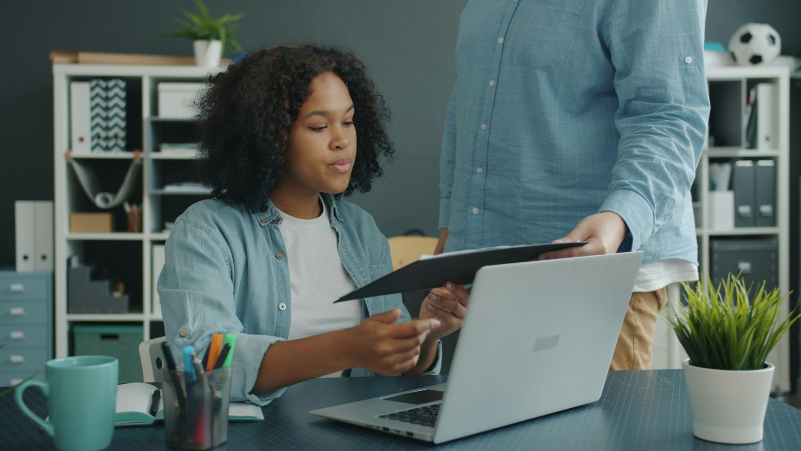 A staff member handing a folder to a colleague at a desk